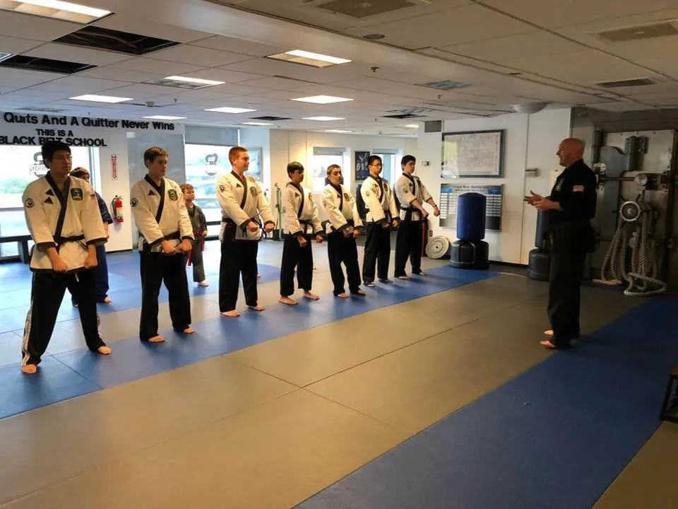 Black belts lined up on the mat